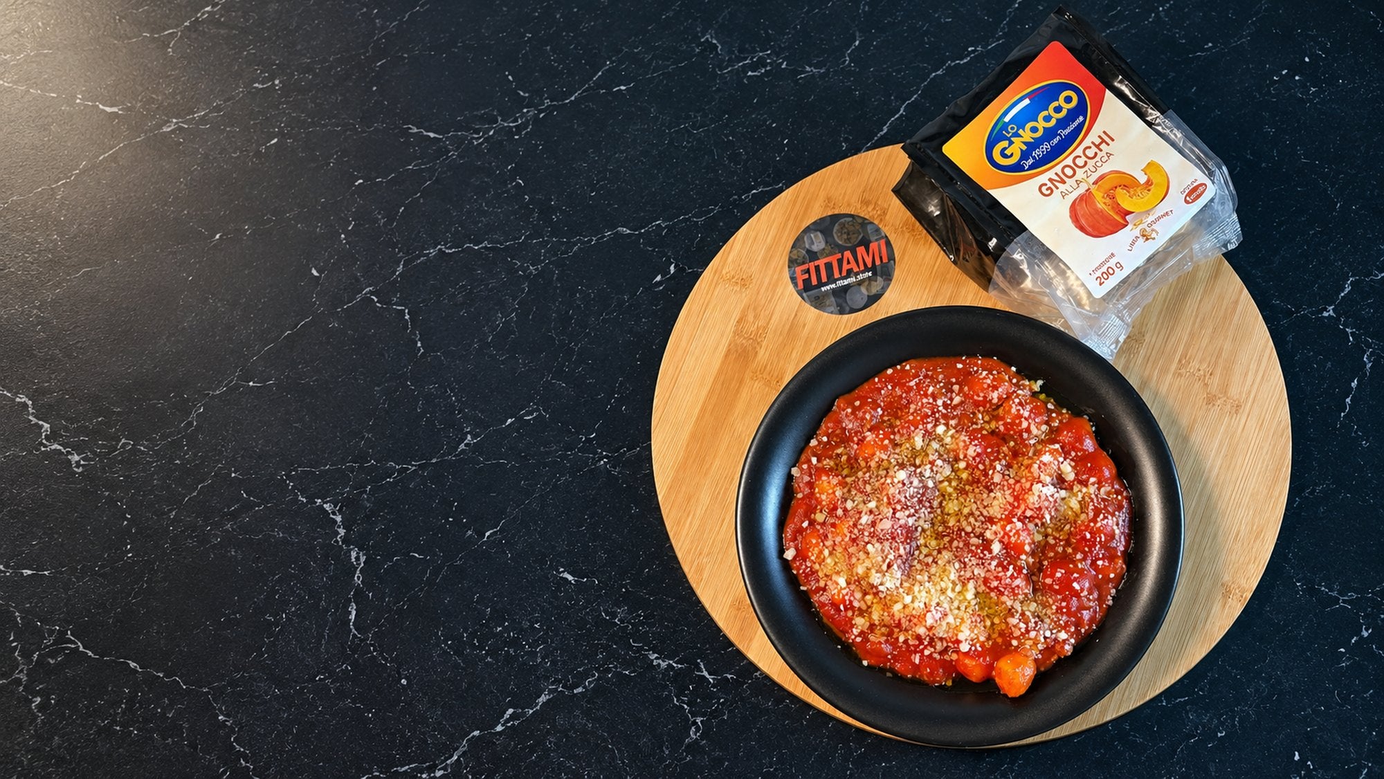 Gnocchi alla zucca conditi al pomodoro in una ciotola nera su un tagliere di legno